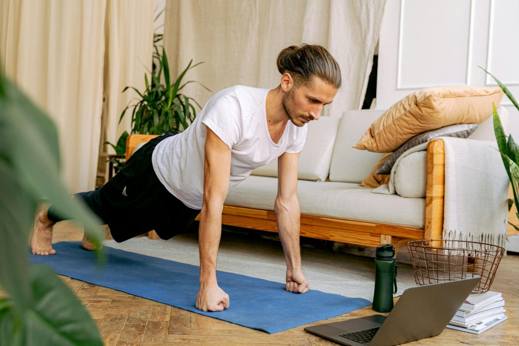Man doing push-ups indoors on a yoga mat, engaging in a healthy lifestyle using online fitness resources.